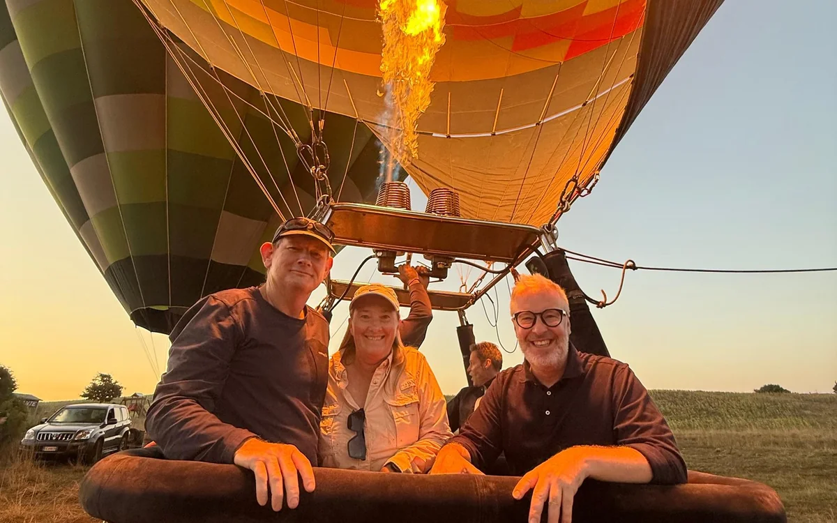 Passengers in a wicker basket as the balloon drifts over Tuscan hills at first light