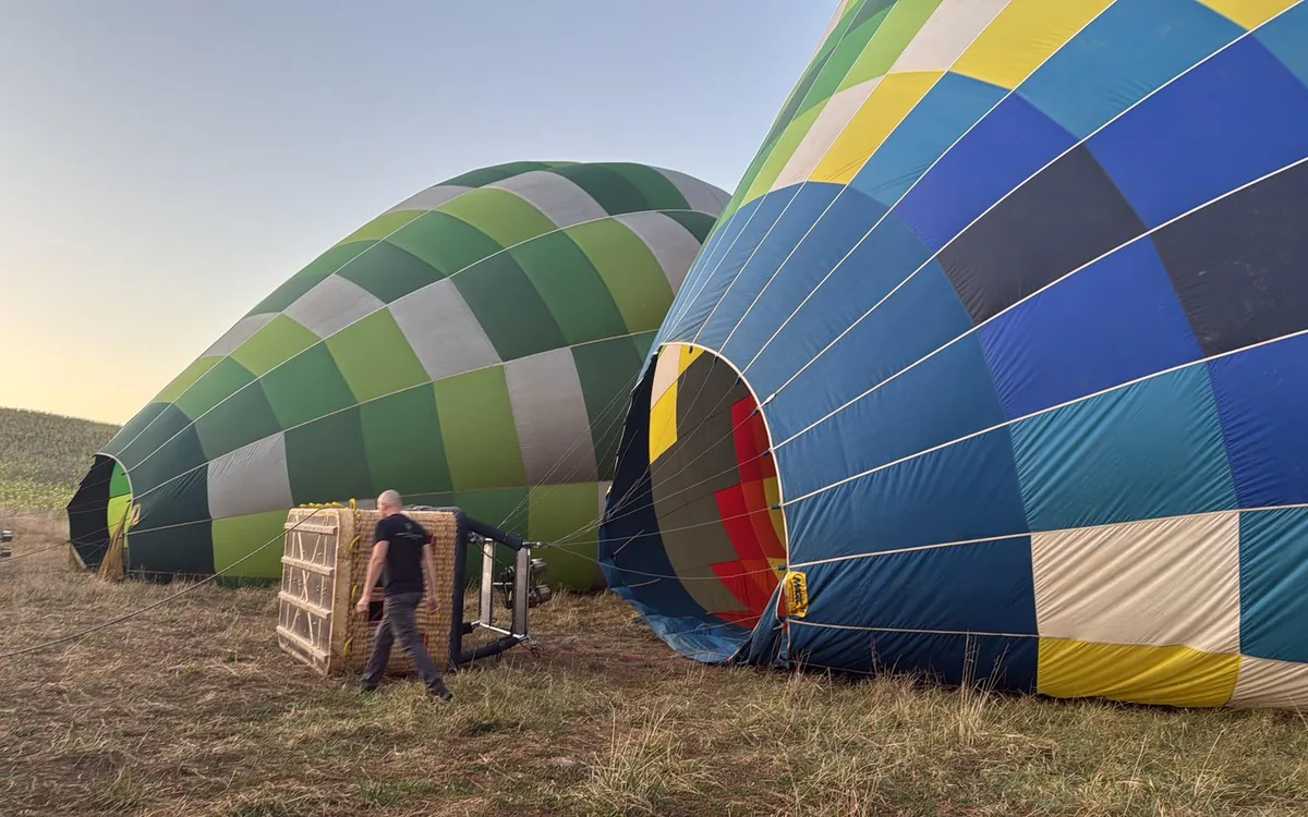 Balloon envelopes being inflated on a Tuscan field before sunrise
